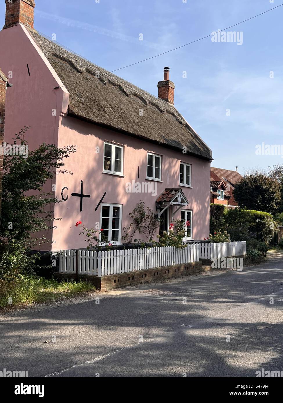 Maison Norfolk rose vif avec toit de chaume Banque D'Images