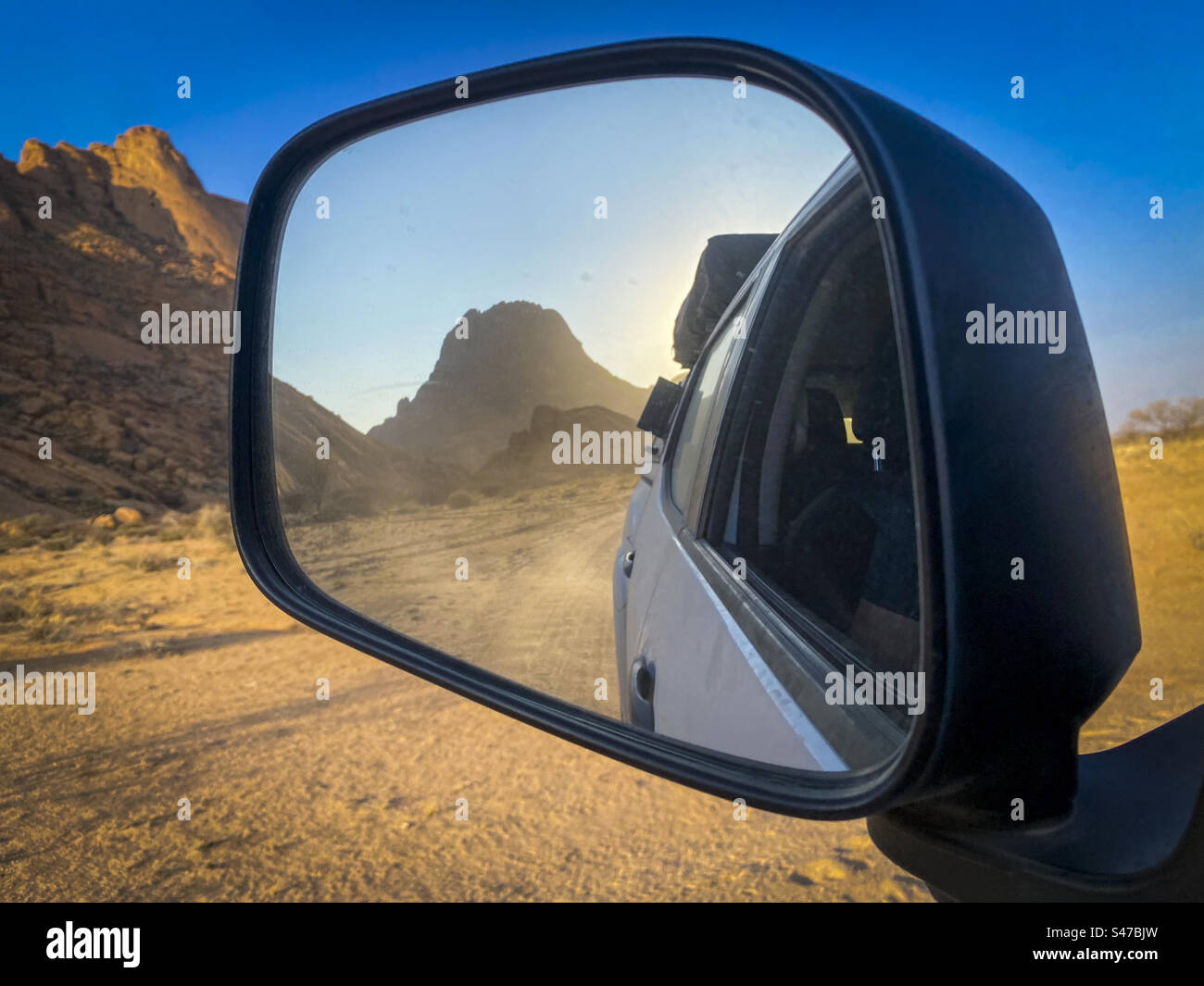 Reflets d'une montagne dans le désert dans le rétroviseur d'une voiture en mouvement en Namibie Banque D'Images