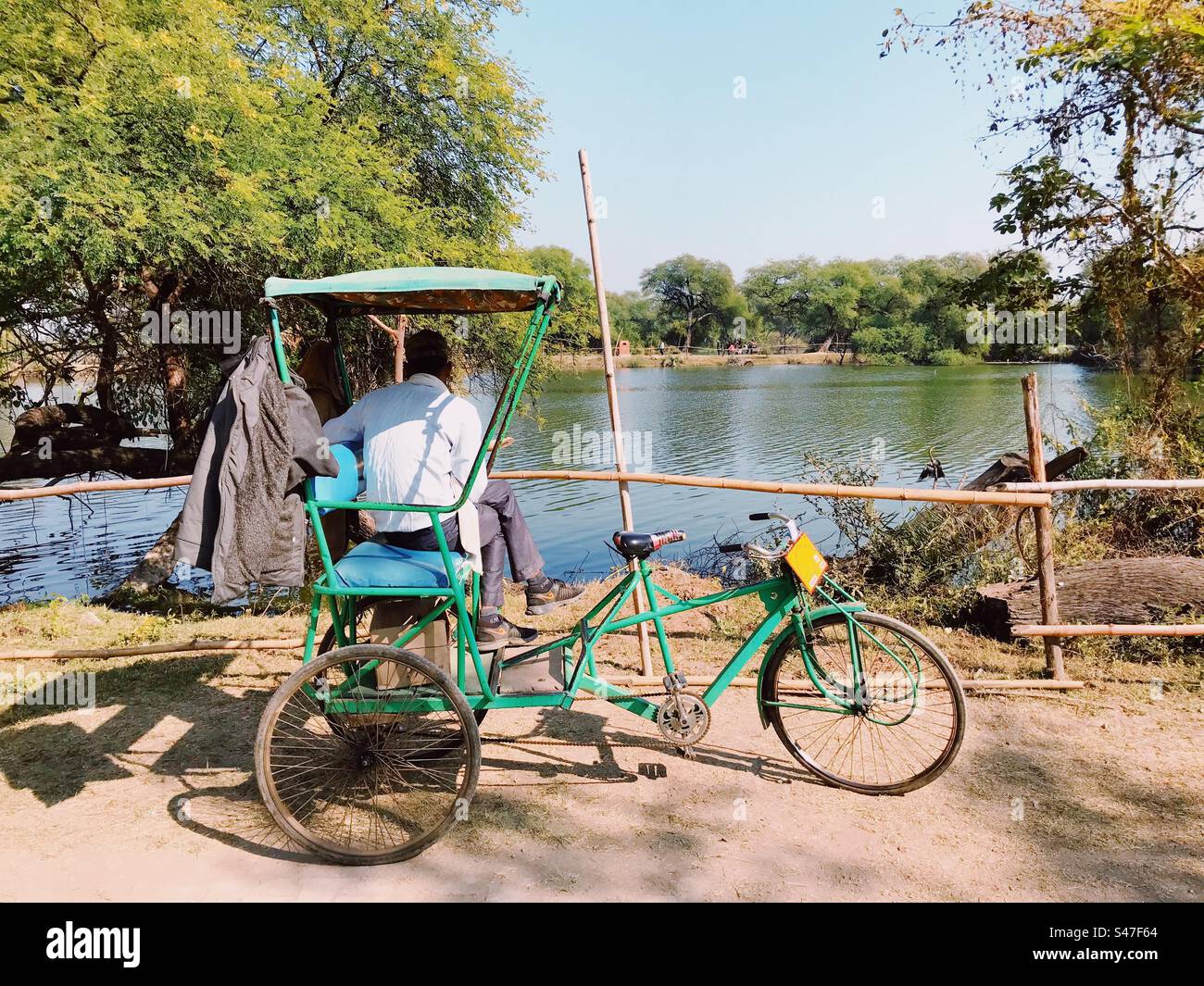 Pousse-pousse à vélo dans le sanctuaire d'oiseaux de Bharatpur au Rajasthan en Inde surplombant un plan d'eau Banque D'Images