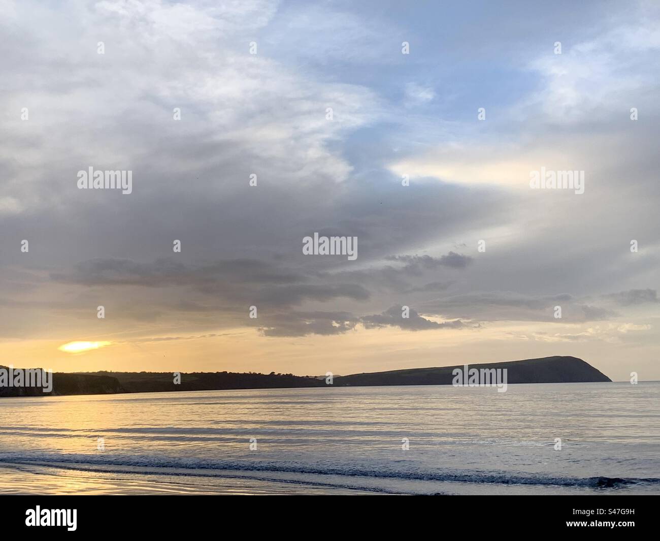 Soleil couchant derrière les nuages et le promontoire sur la mer, les sables de Newport, le Pembrokeshire - Image de stock capturée avec un smartphone