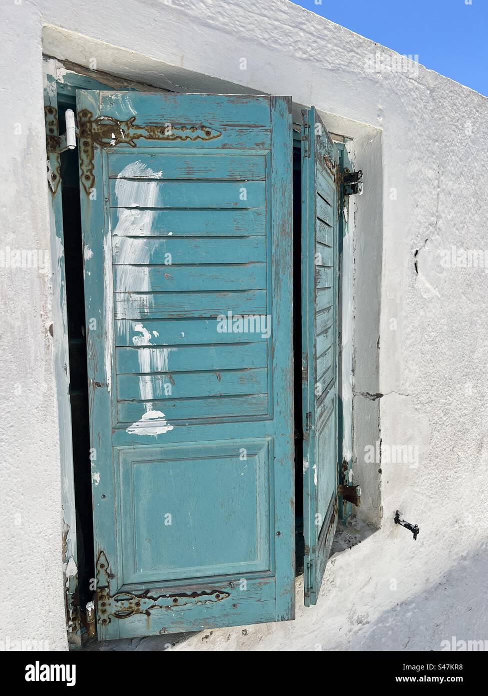 Des volets rustiques peints sarcelle sur un bâtiment blanchi à la chaux dans le village d'Akrotiri, île de Santorin. Banque D'Images