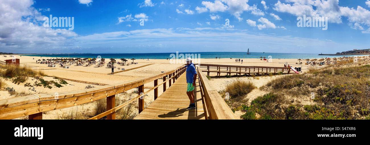 Homme debout dans une promenade en bois avec la plage de Meia Praia à Lagos Portugal Banque D'Images