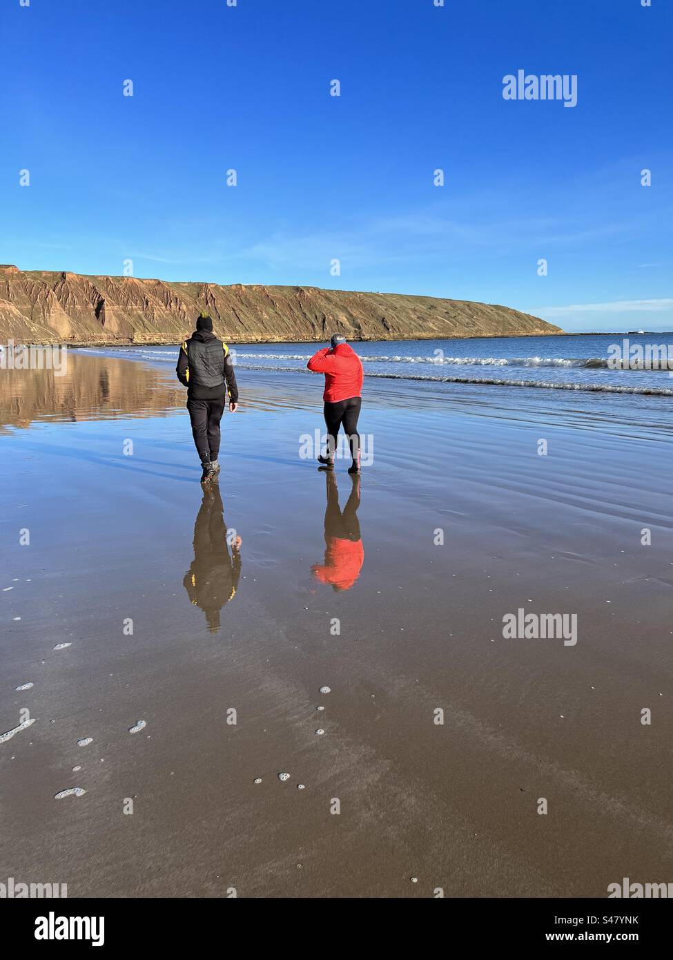 Couple réfléchi sur une plage humide en hiver Banque D'Images
