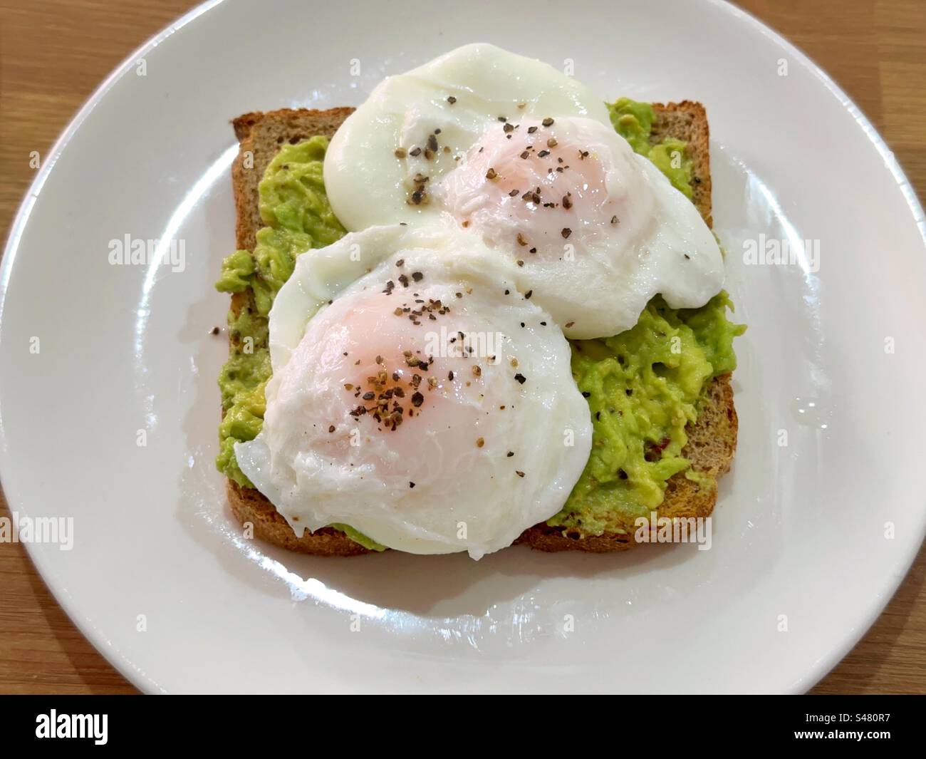 Vue rapprochée de deux œufs pochés sur un toast à l'avocat avec du poivre noir Banque D'Images