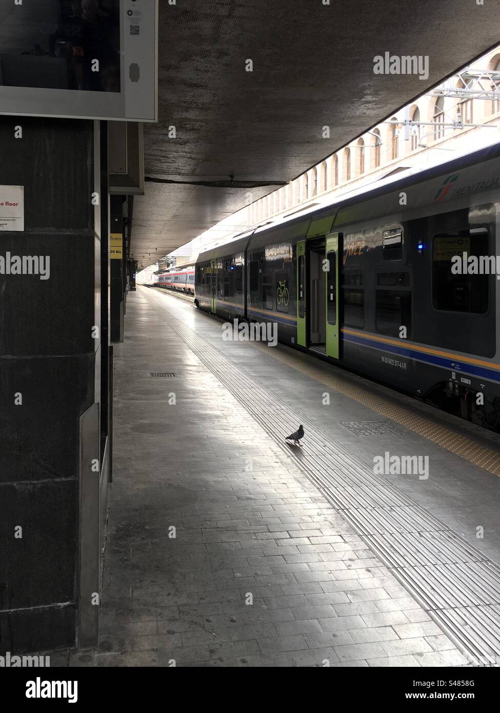 Marciapiede della stazione Termini di Roma, Italia, vuoto, senza viaggiatori. Solo un piccione. Binari. Treni regionali in Partenza. Banque D'Images