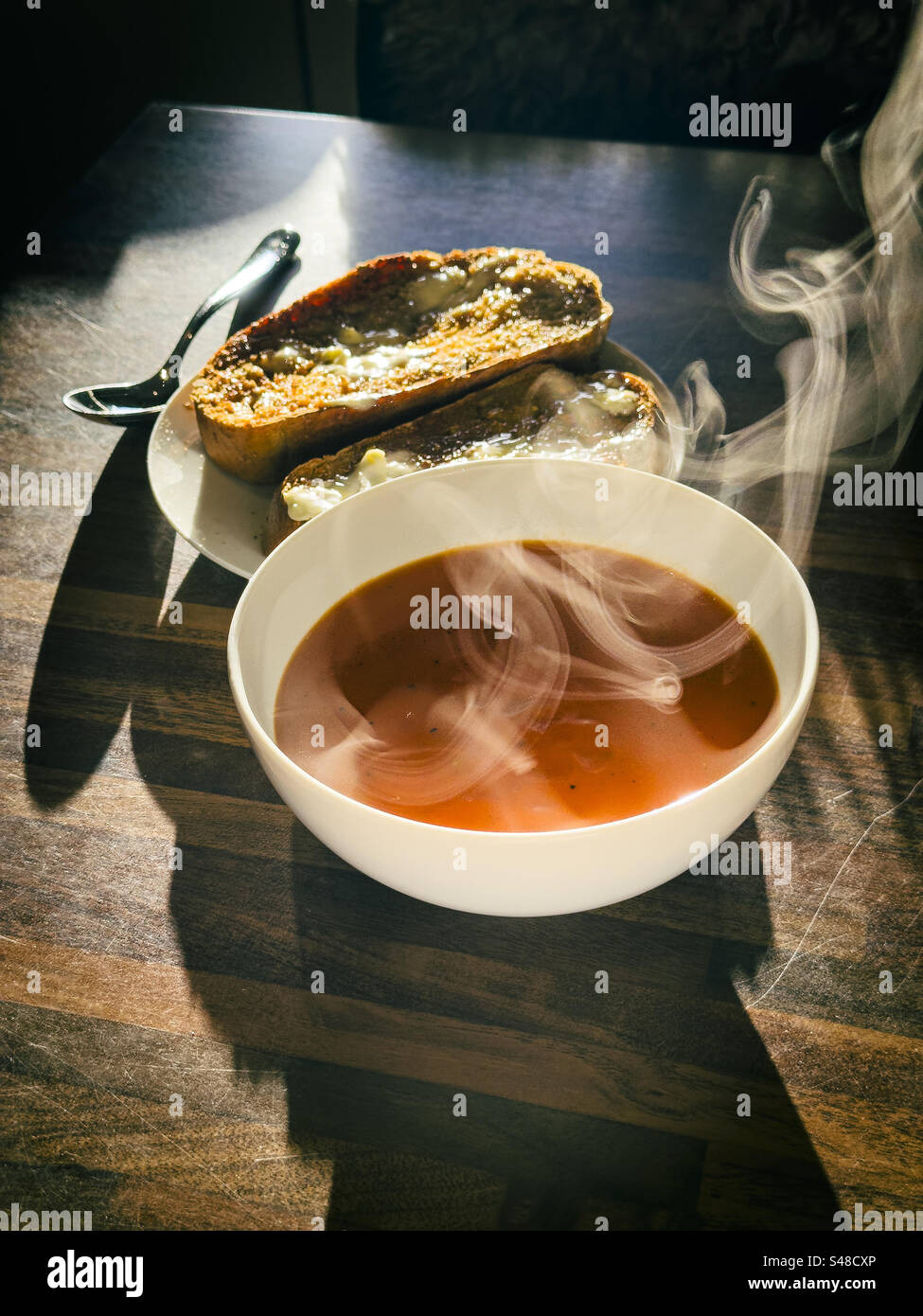 Soupe de tomates et toast sur une table de cuisine avec montée de vapeur : Phillip Roberts - Image de stock capturée avec un smartphone