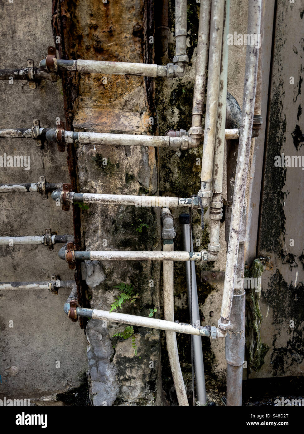 Infrastructure de plomberie vieillissante dans l'allée derrière le bâtiment dans la ville urbaine dense Banque D'Images