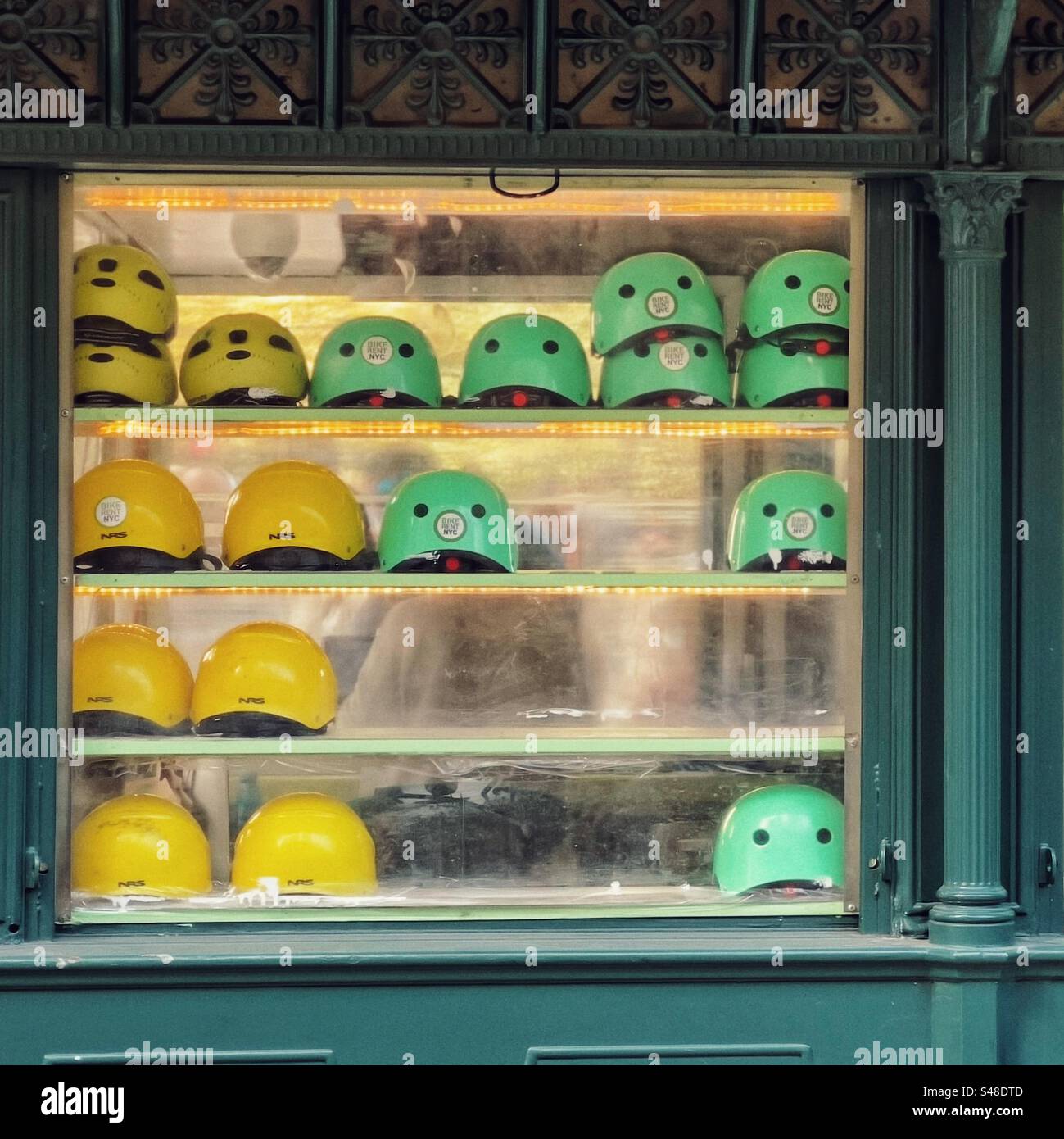 Casques de vélo vert et jaune dans le kiosque de location de vélo à Central Park à New York Banque D'Images