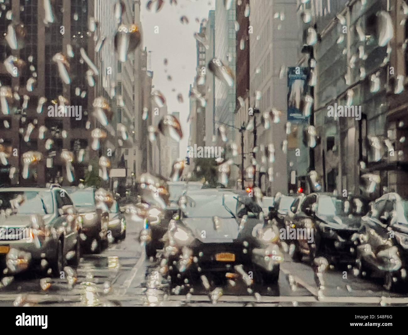 La circulation s'est arrêtée aux feux de la ville de New York vu à travers une fenêtre éclaboussée de pluie Banque D'Images