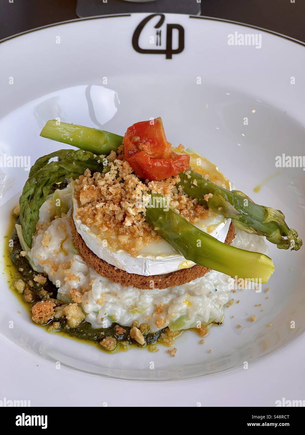 Plan rapproché d'un Risotto gastronomique reconstruit avec du riz blanc, des asperges, du crumble, des poivrons sur une assiette de restaurant à plat profond dans un restaurant français à Montpellier, France - Image de stock capturée avec un smartphone