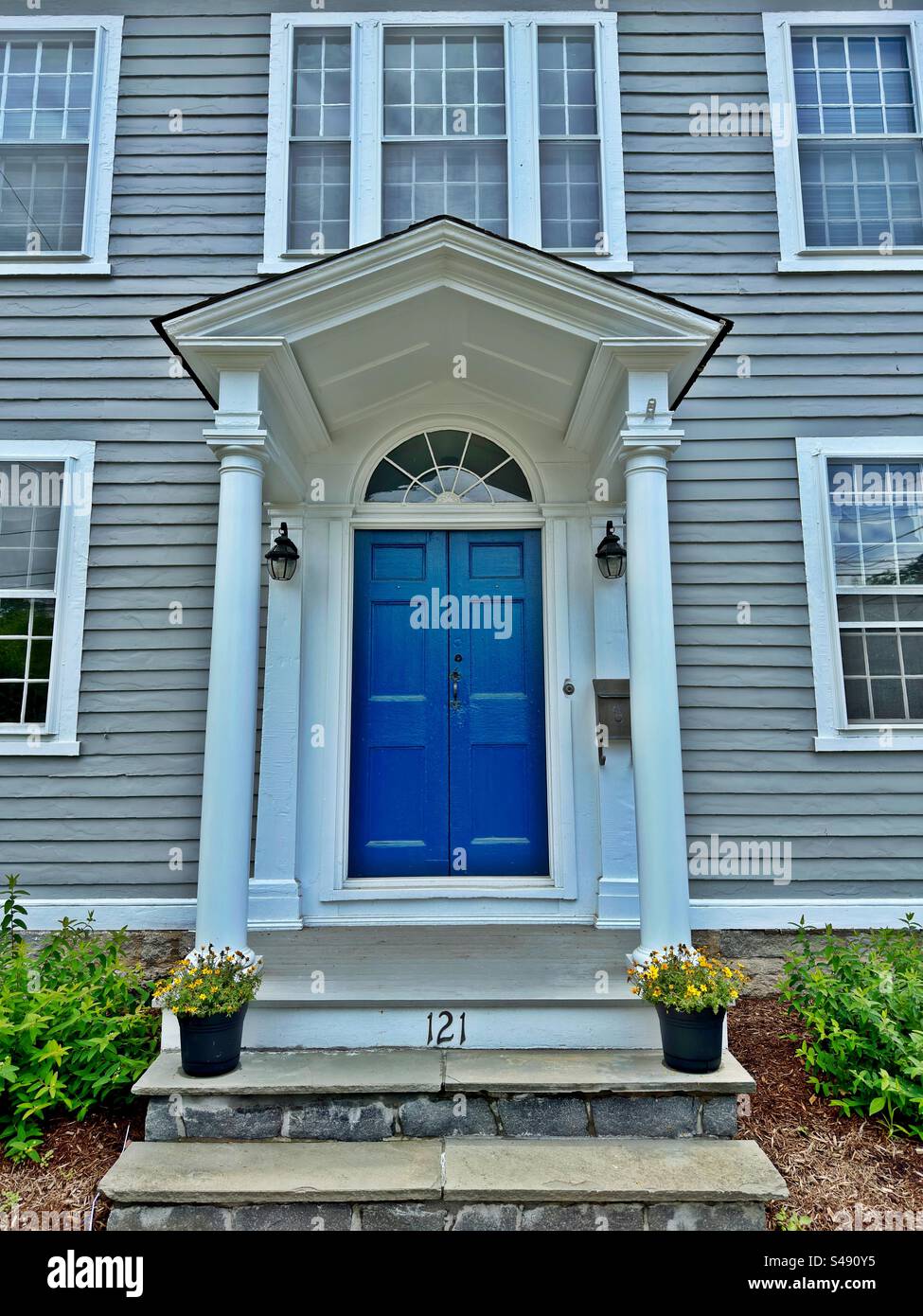 Porte bleue sur maison grise à Guilford, Connecticut, USA. Architecture vintage. Entrée avec marches en ardoise et pots de fleurs. Banque D'Images