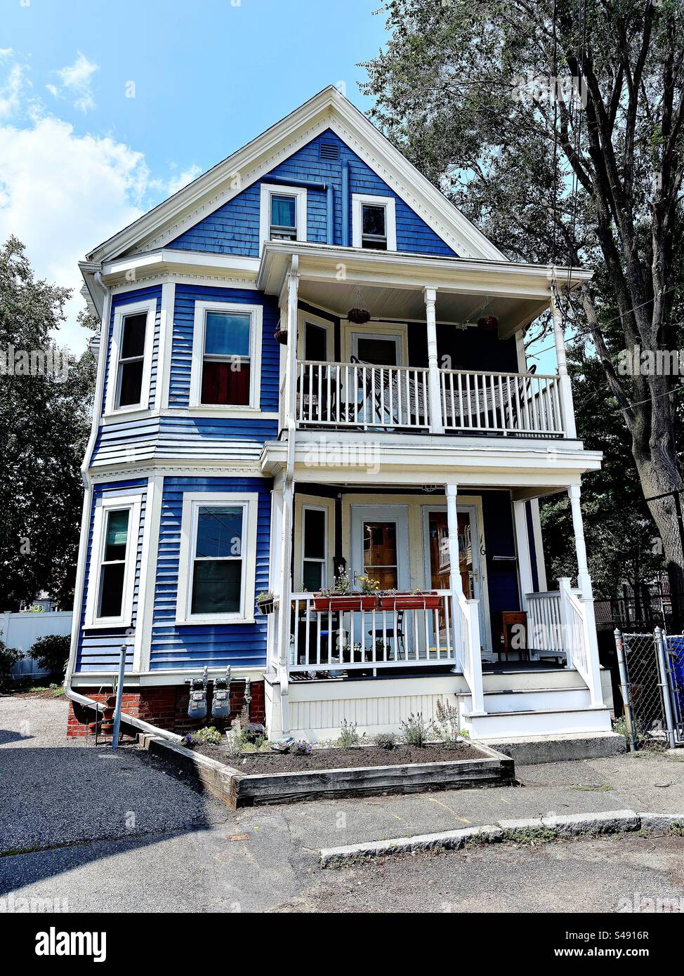 Résidence en bois de trois étages dans le quartier Davis Square de Somerville, Massachusetts, États-Unis. Bâtiment bleu avec garniture blanche et 2 porches. Banque D'Images