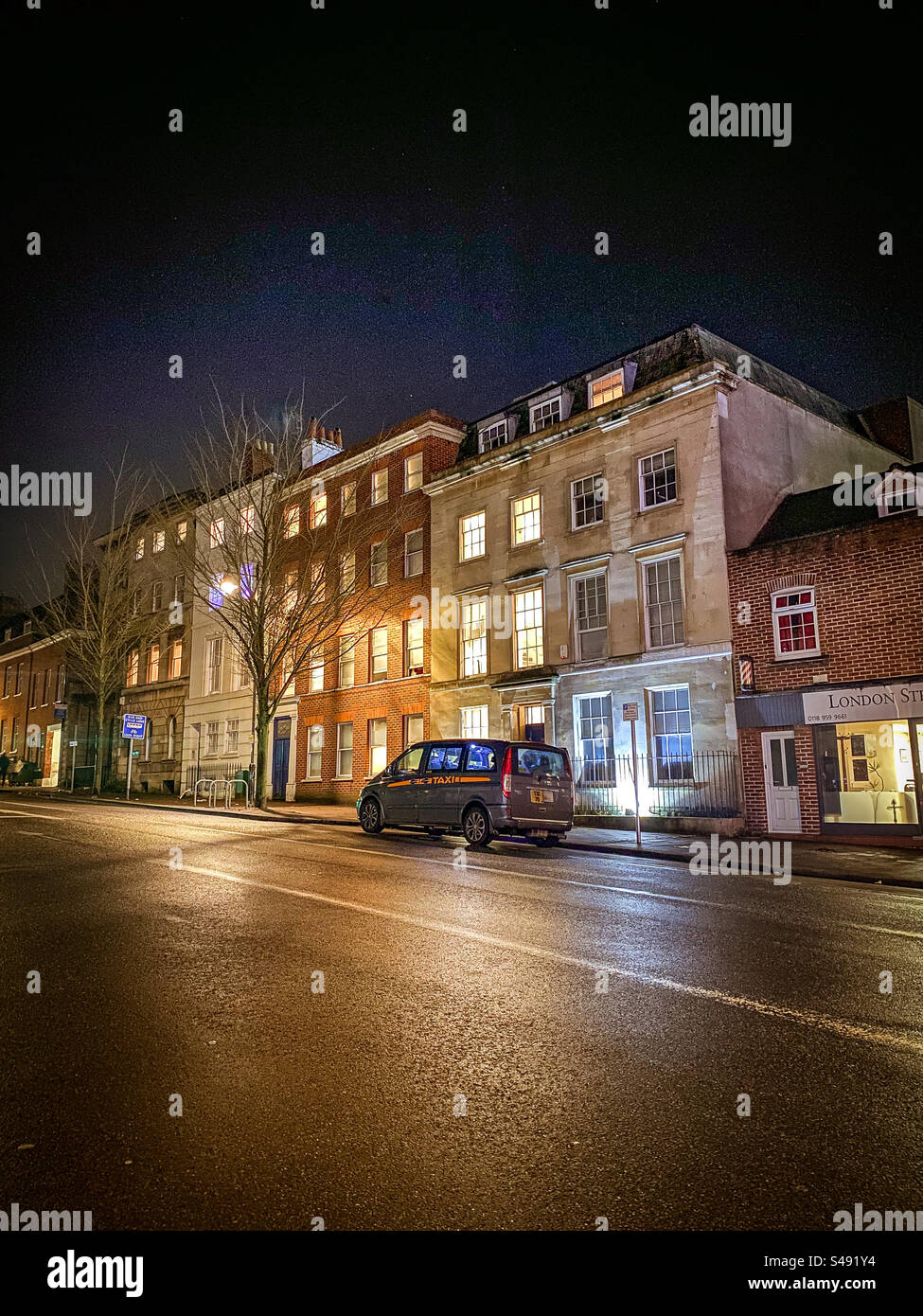 Un taxi attend à l'extérieur des immeubles la nuit. Banque D'Images