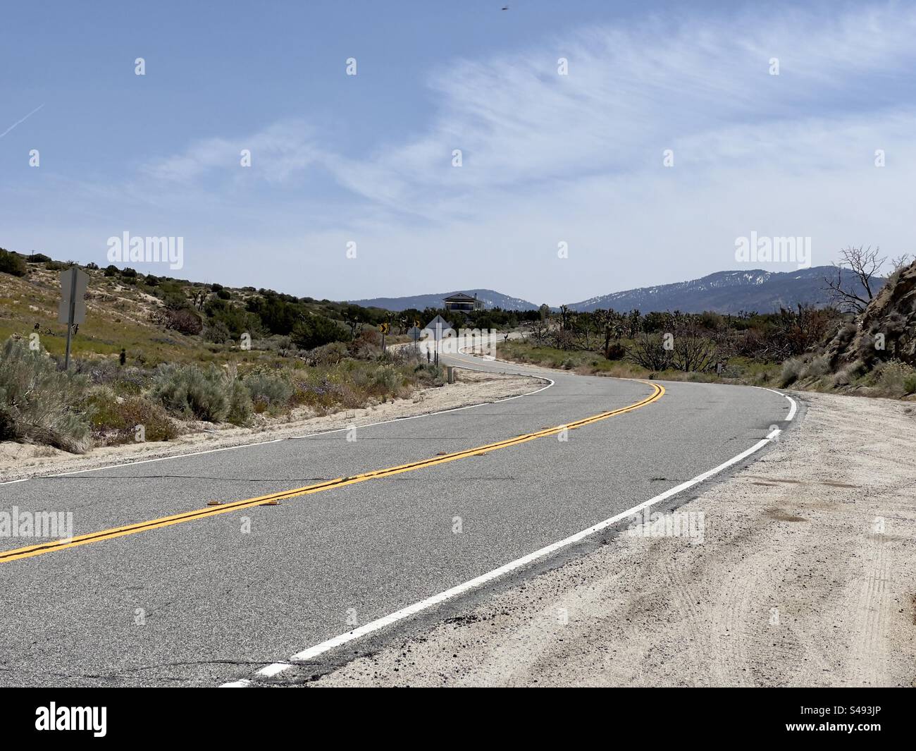 Route sinueuse vide à travers le désert, avec des montagnes en arrière-plan, dans le sud de la Californie, USA Banque D'Images