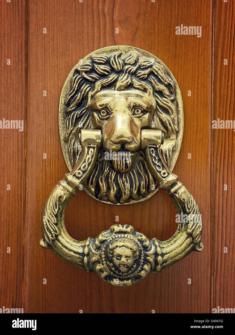 Ancienne poignée de porte dorée en forme de tête de lion à Córdoba, Espagne. - Image de stock capturée avec un smartphone