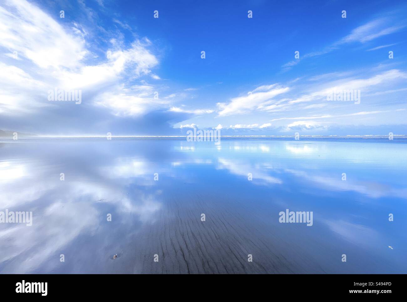 Un ciel bleu reflétait à marée basse sur la plage Banque D'Images