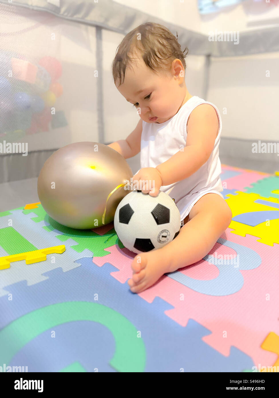 Bébé d'un an avec un ballon et un ballon de football Banque D'Images