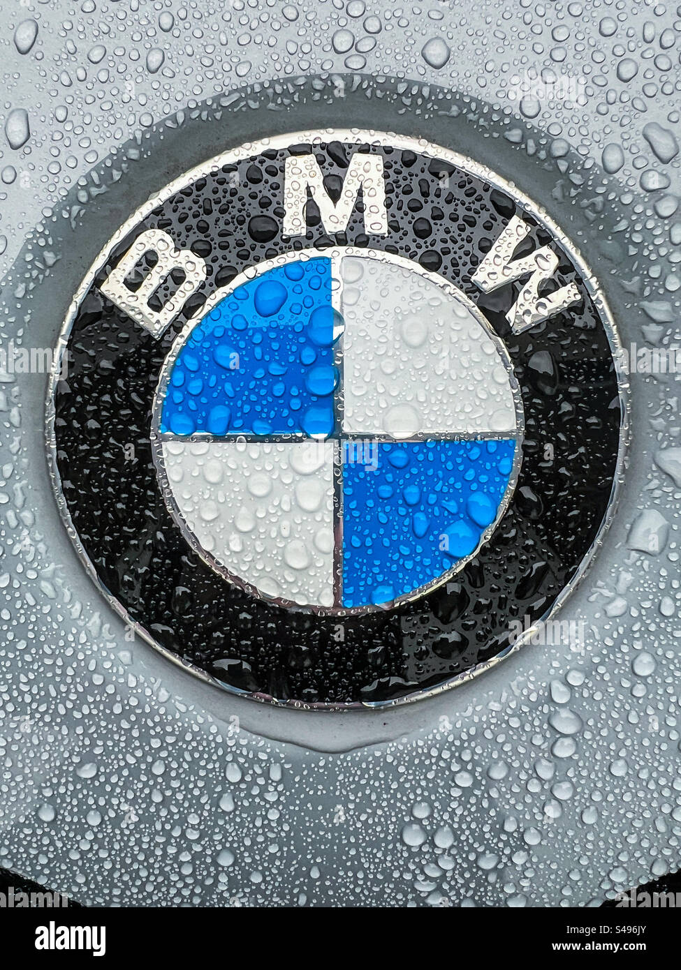 Gros plan d'un badge BMW sur un véhicule sous la pluie - Image de stock capturée avec un smartphone