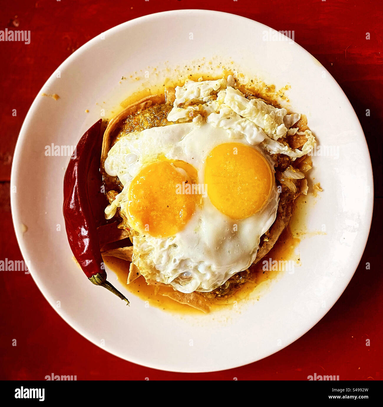 Deux œufs au plat sur une sauce tomate épicée verte avec un piment rouge hoy pour le petit déjeuner au Mexique Banque D'Images