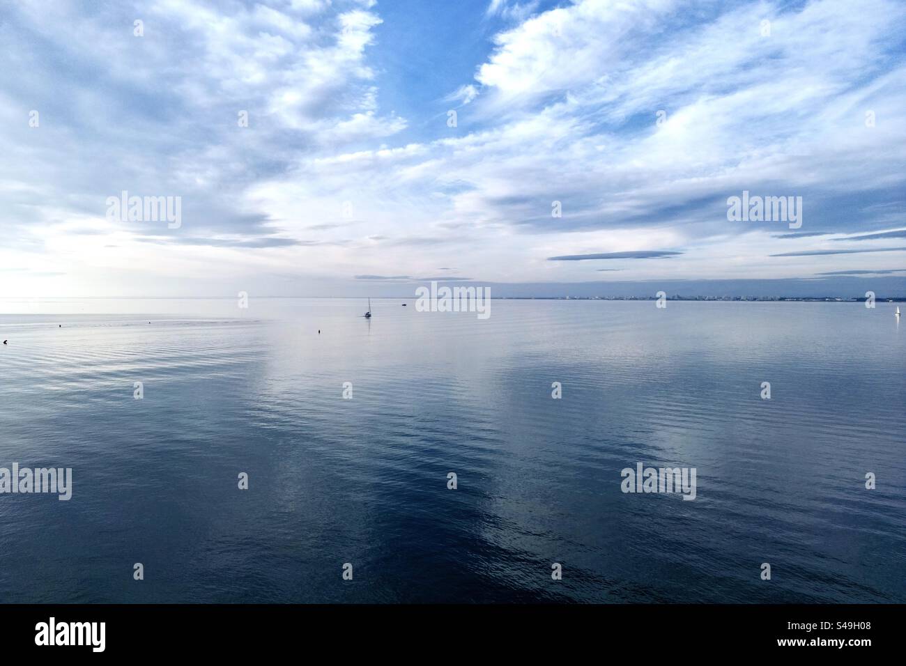 Vue de paysage bleu du soleil se couchant derrière les nuages se reflétant dans l'eau vu de Port Camargue, Occitanie, France. - Image de stock capturée avec un smartphone