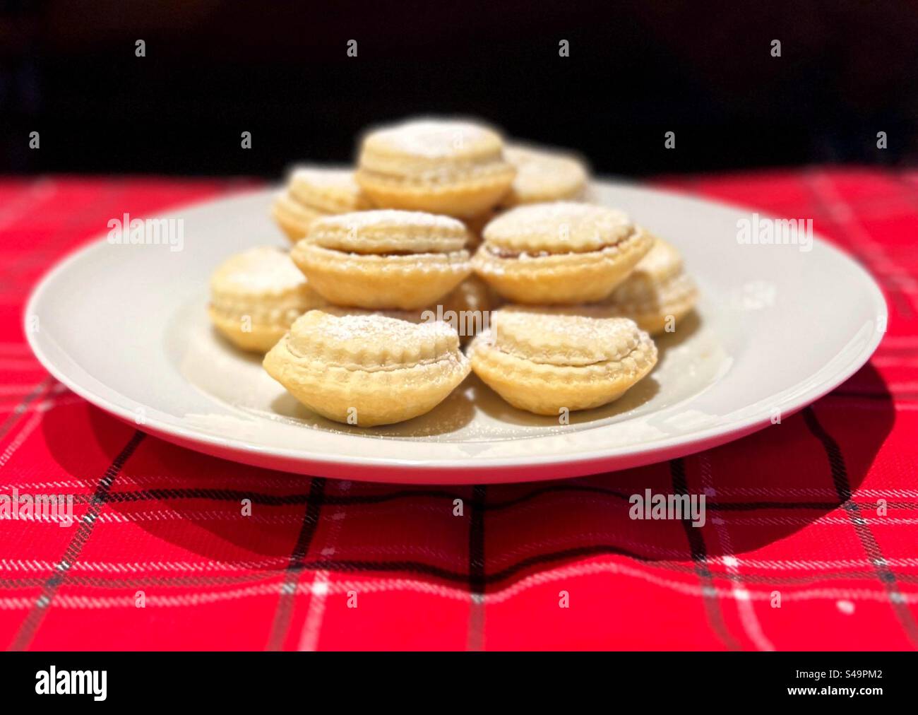 Assiette de tartes hachées de Noël maison sur une nappe à carreaux rouges. Banque D'Images