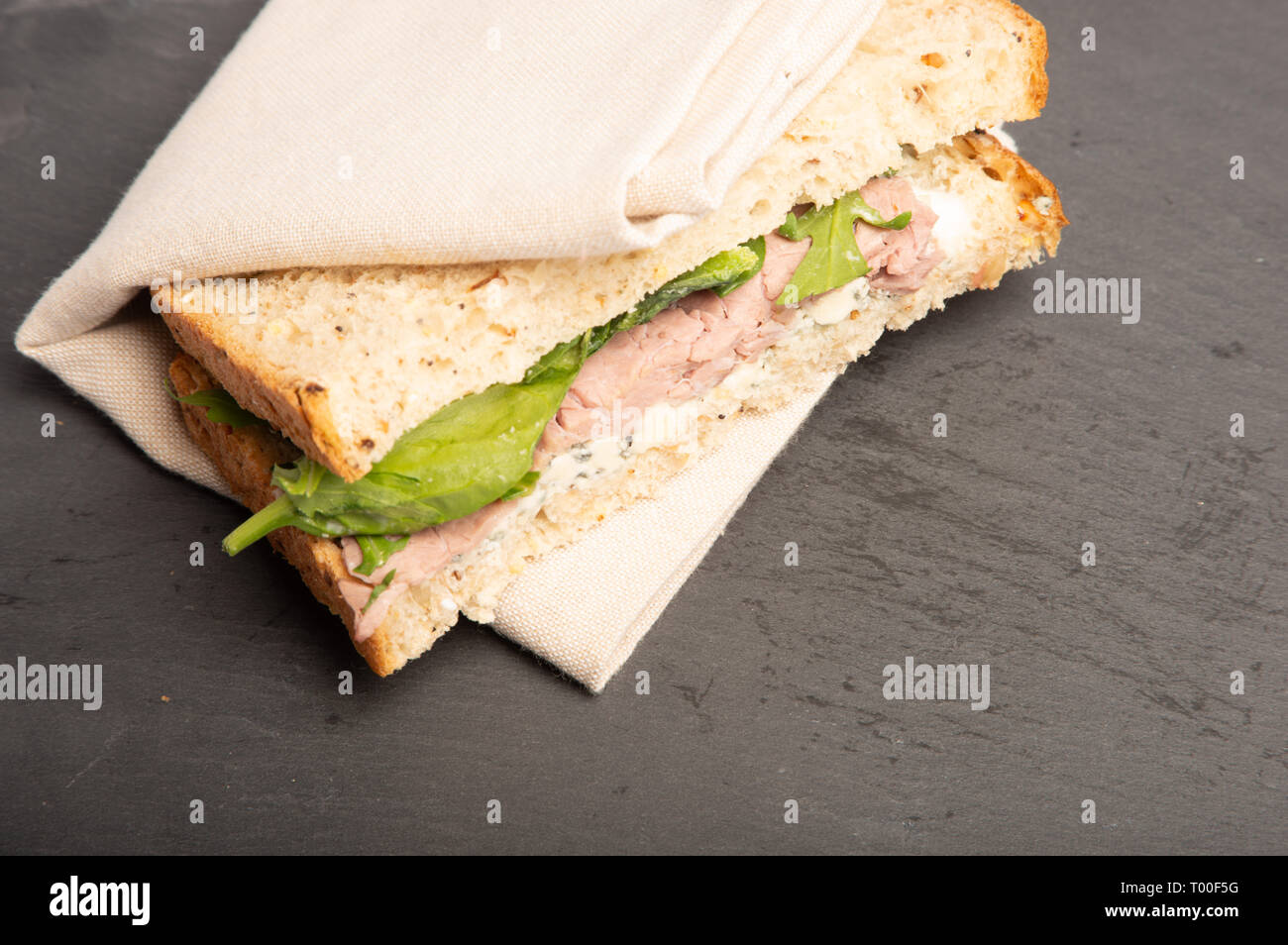 Le pain de grains entiers de sandwich steak, Stilton et épinards. délicieux déjeuner temps repas. organique avec aucun utiliser, sur une surface gris ardoise. Banque D'Images