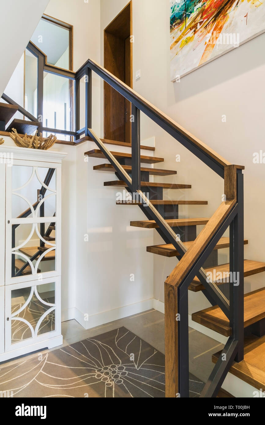 Escaliers en bois de noyer avec black métal et bois clair haut de la rampe  en verre menant à partir de la chambre en sous-sol à l'étage principal à  l'intérieur contemporain de