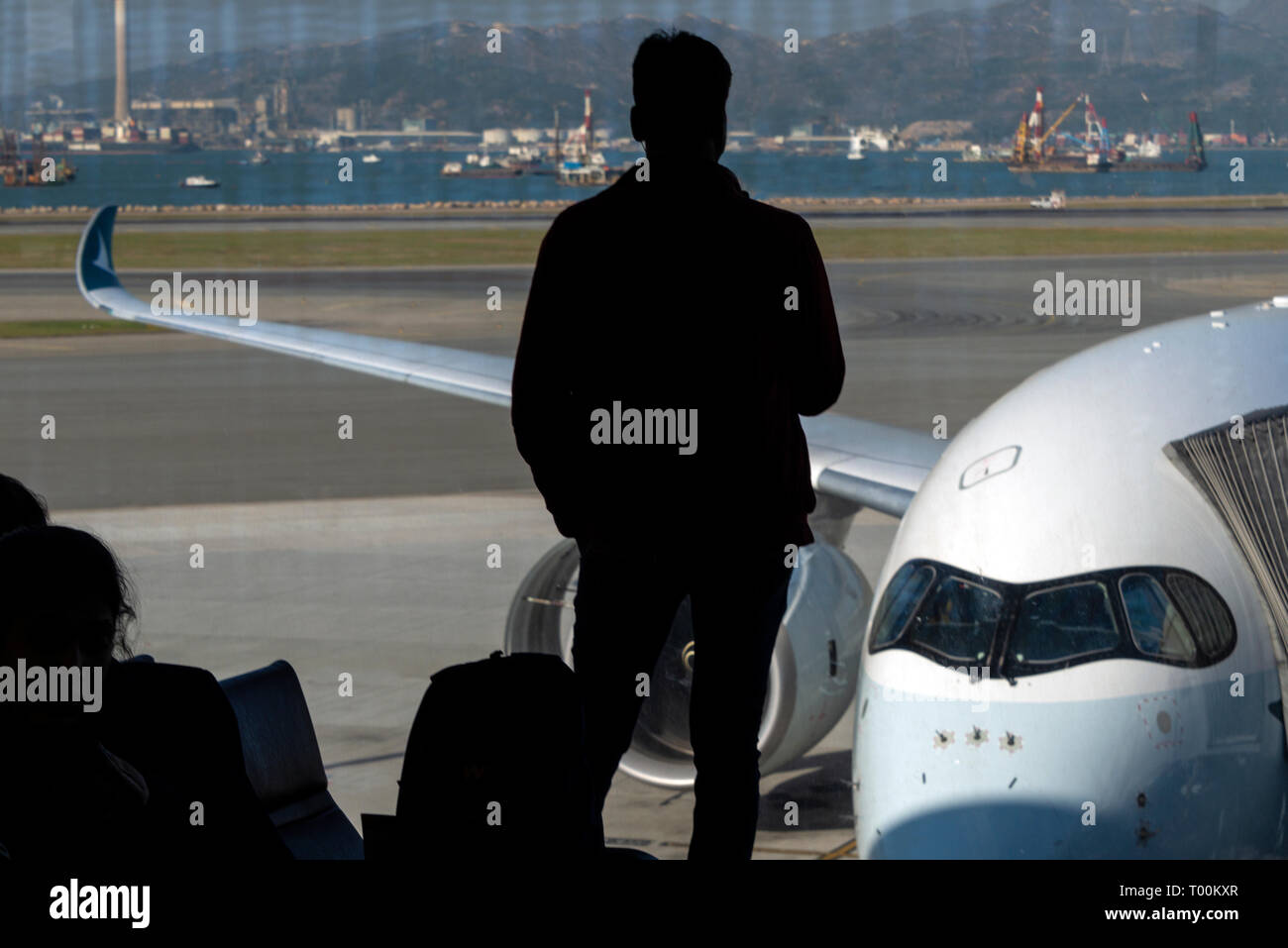 Silhouette d'un passager à la porte d'embarquement, fenêtre, attendant à bord d'un avion de ligne Airbus A350, de l'aéroport de Hong Kong. Banque D'Images