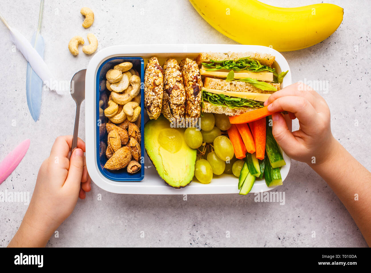 School healthy lunch box avec sandwich, des biscuits, des noix, des fruits et de l'avocat sur un fond blanc. Banque D'Images