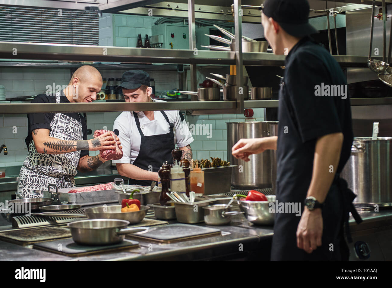 C'est fresh chef professionnel en tenant un plateau de viande rouge et de l'enseignement ses assistants comment le choisir pour la cuisson. L'école culinaire Banque D'Images