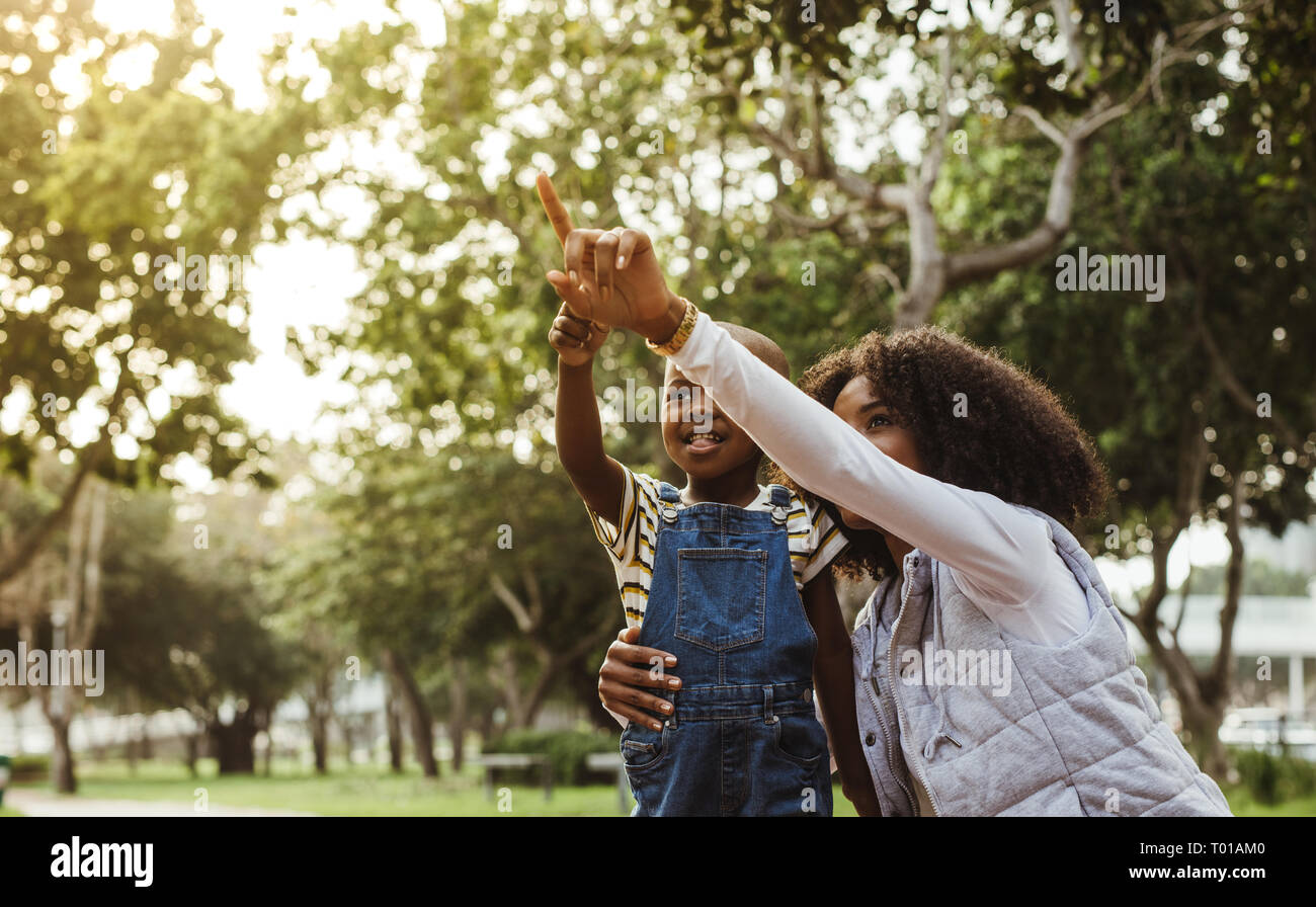 Femme africaine pointant son doigt et dire à son fils de regarder une vue dans le parc. Mère avec son joli fils de passer du temps ensemble dans le parc. Banque D'Images