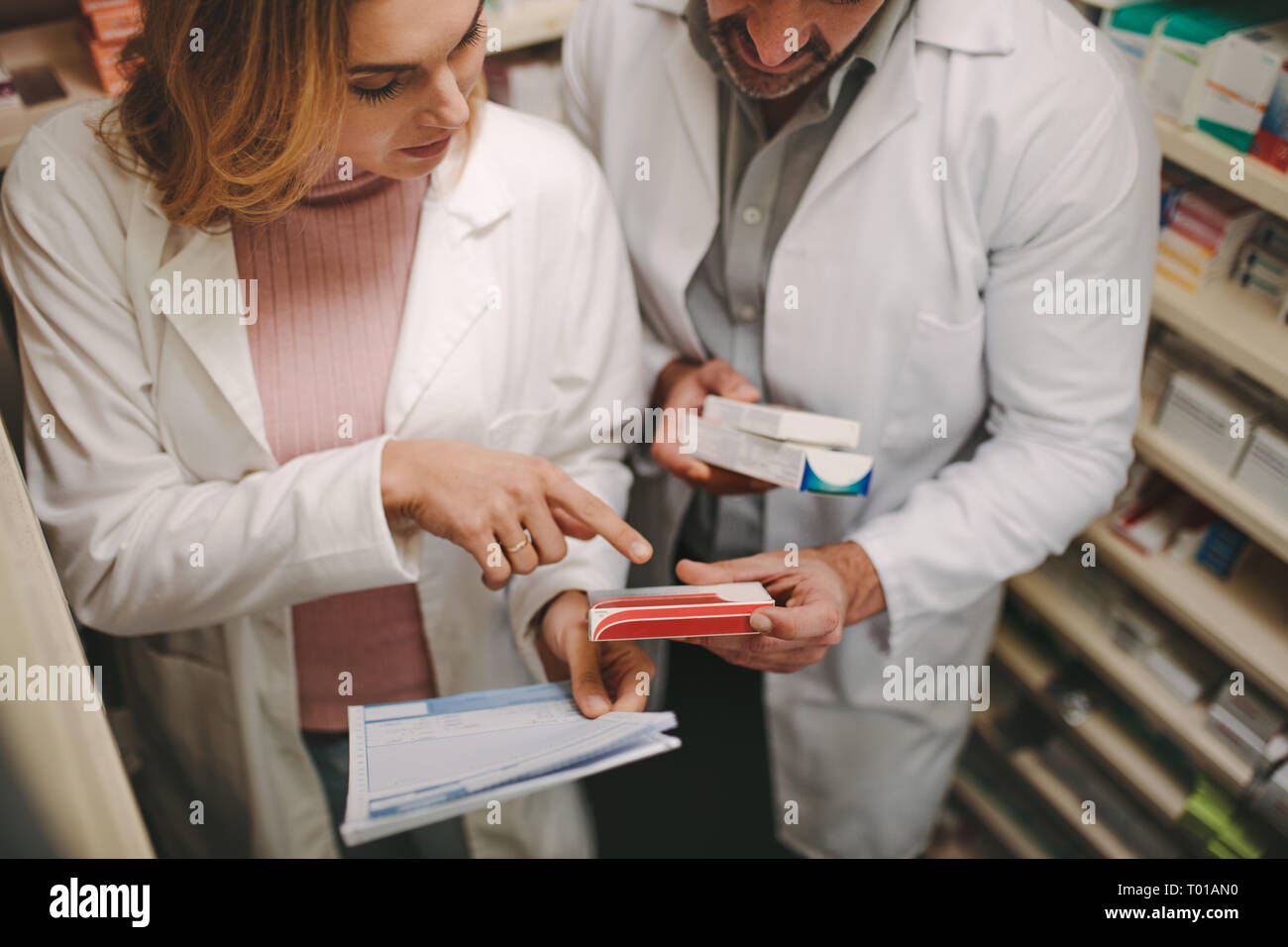 Chimiste femelle avec prescription pointing at medicine fort chez un collègue de drug store. Pharmacie avec une prescription à bon médicament Banque D'Images