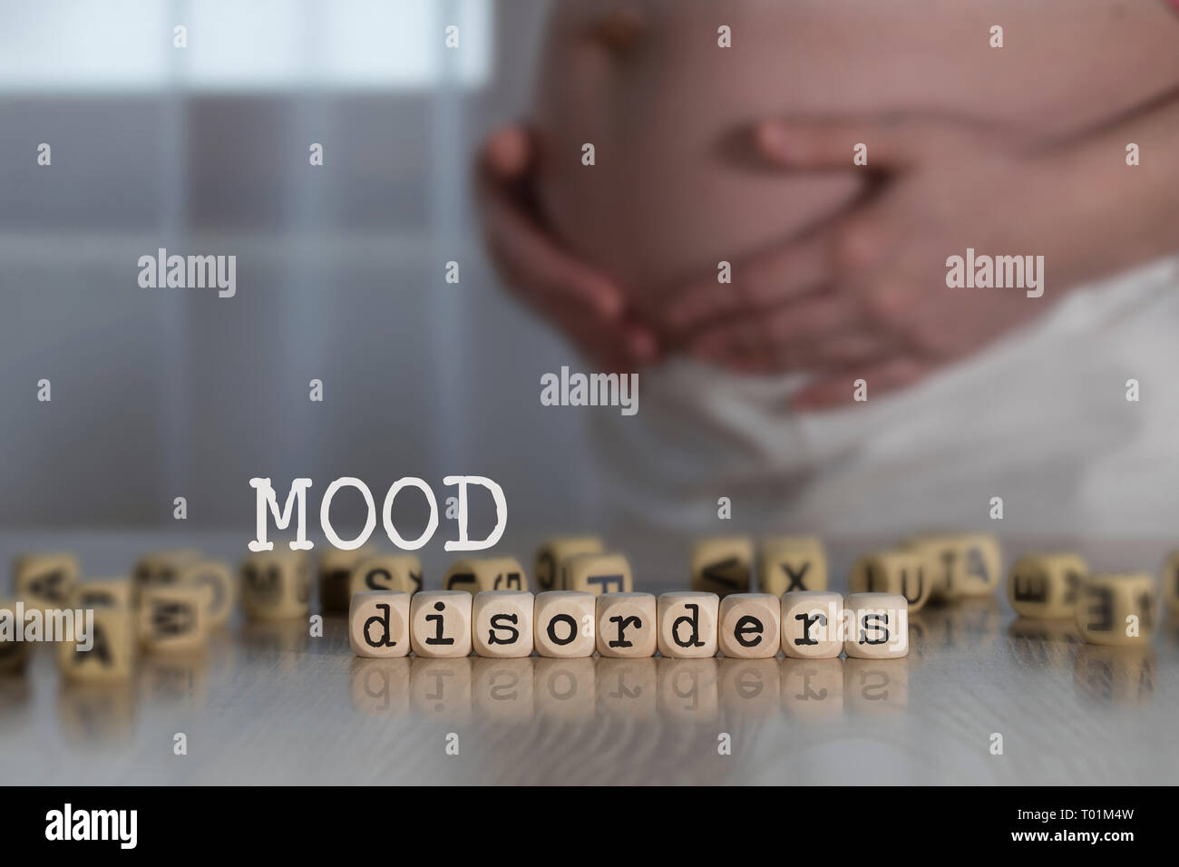 Les troubles de l'humeur des mots composés de lettres en bois. Femme enceinte à l'arrière-plan Banque D'Images