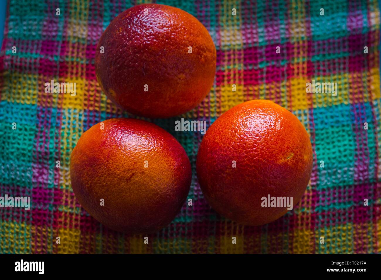 Plusieurs oranges rouges frais viennent d'être choisis à partir d'un arbre et empilés sur un tissu à carreaux de diverses couleurs pour vendre ou faire de savoureux. Banque D'Images Plusieurs oranges rouges frais viennent d'être choisis à partir d'un arbre et empilés sur un tissu à carreaux de diverses couleurs pour vendre ou faire de savoureux. Banque D'Images