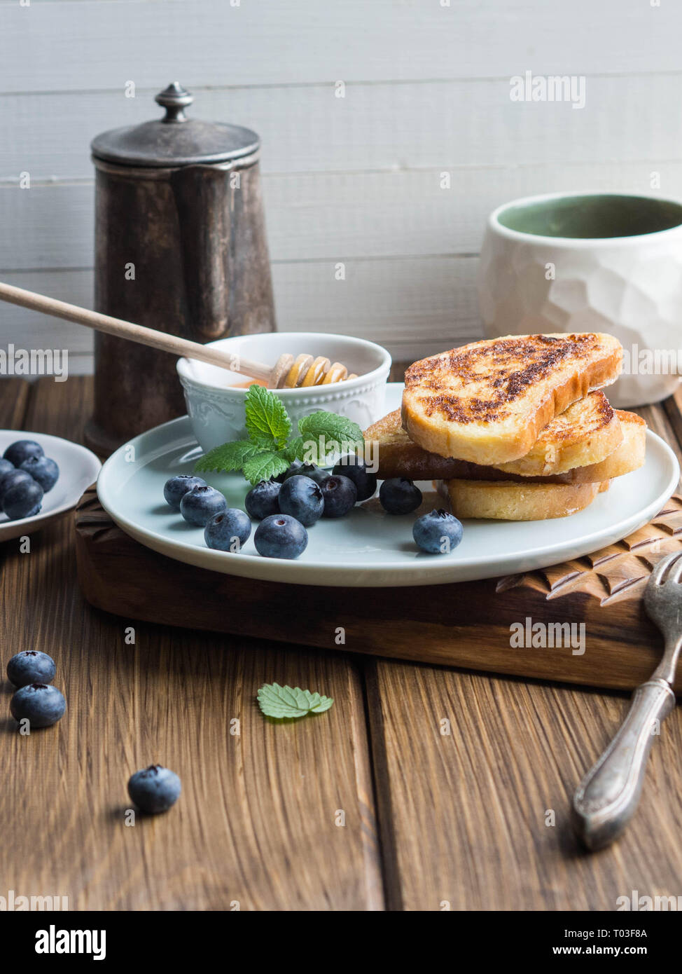 Une pile de toasts maison saupoudré de bleuets et de miel sur une plaque bleue sur une texture en bois conseil. Bon petit déjeuner. Banque D'Images