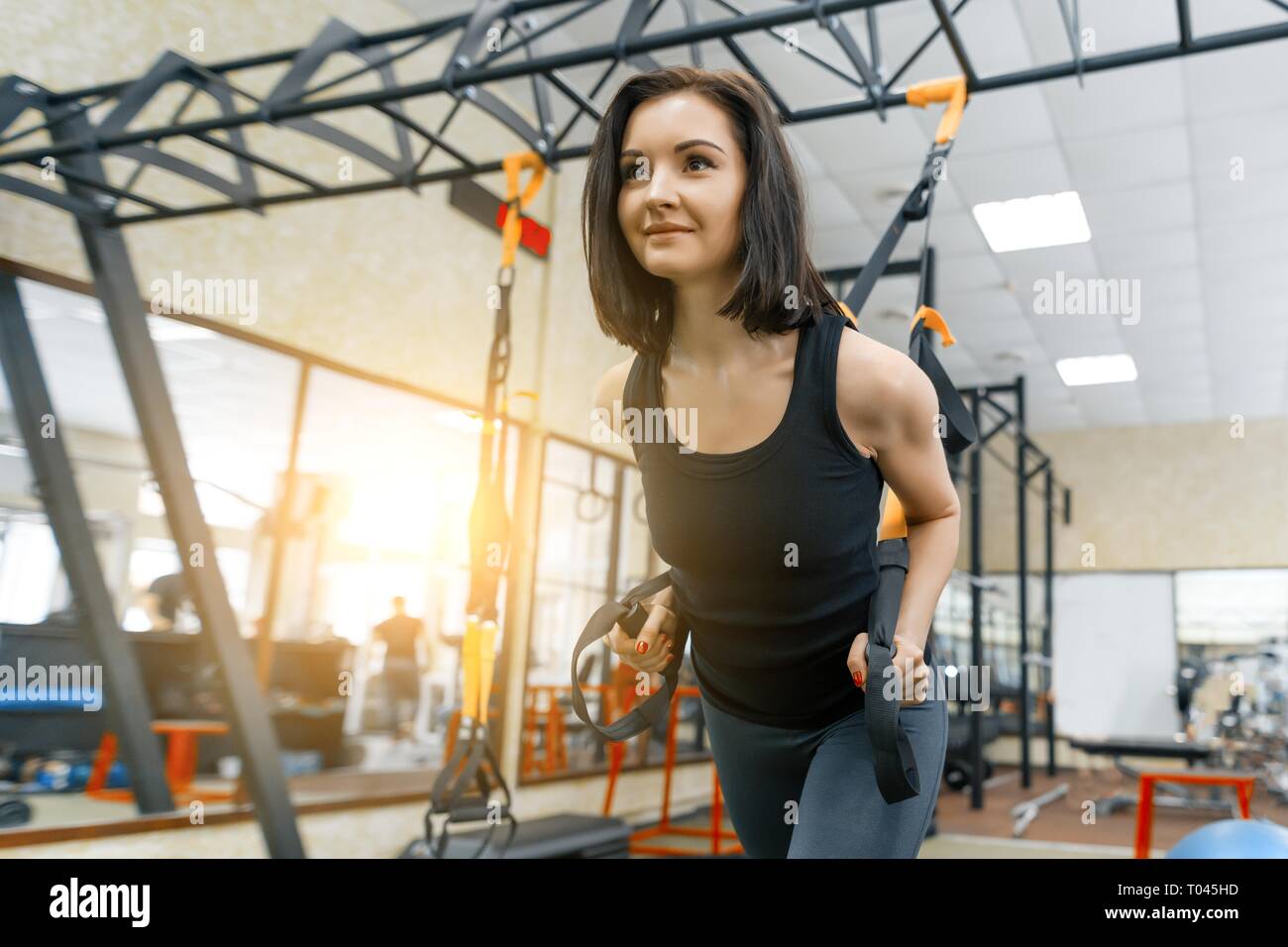 Jeune femme dans la salle de sport faire des exercices de remise en forme à l'aide de sangles sport système, tenant les mains par les boucles. Fitness, le sport, la formation, les gens concept Banque D'Images