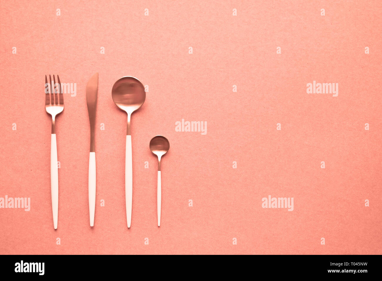 Ensemble de coutellerie sur fond corail vivant, vue du dessus, copiez l'espace. Set de table, menu design. Corail vivant - couleur de l'année 2019 16-1546. Banque D'Images