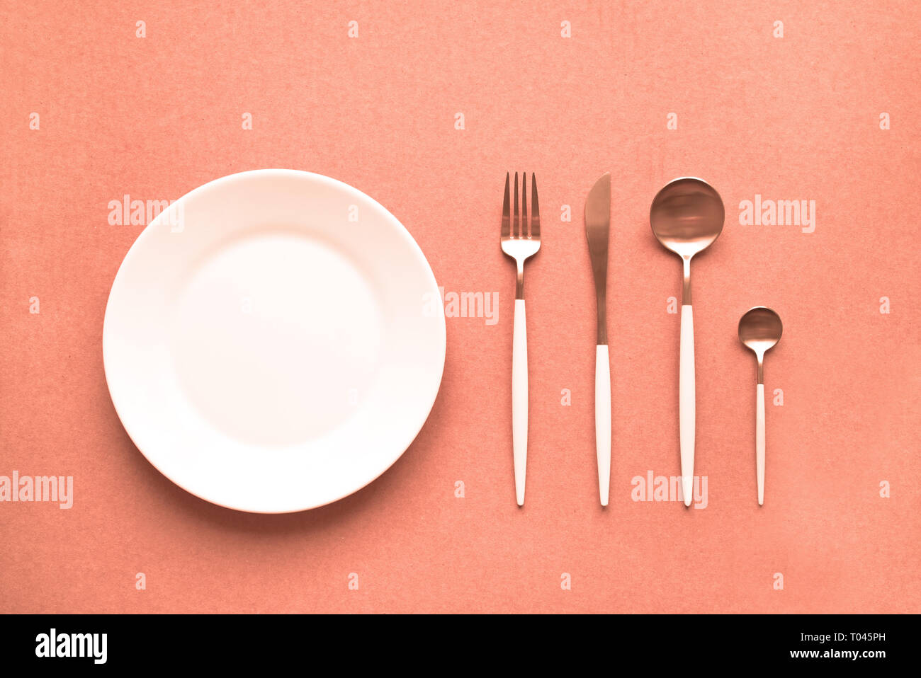 Corail vivant table. Ensemble de couverts et la plaque sur fond corail vivant, vue du dessus, copiez l'espace. Corail vivant - couleur de l'année 2019 16-1546. Banque D'Images