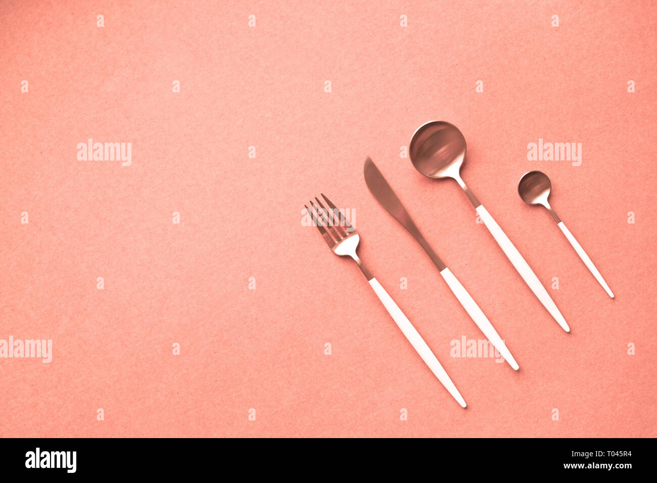 Corail vivant table. Ensemble de coutellerie sur fond corail vivant, vue du dessus, copiez l'espace. Corail vivant - couleur de l'année 2019 16-1546. Banque D'Images