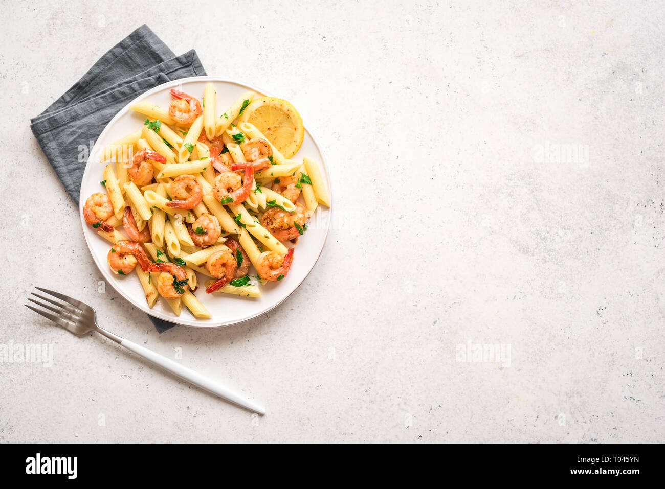 Pâtes penne aux gambas ou crevettes, vue du dessus, copiez l'espace. Crevettes sautées au citron avec des pâtes, fruits de mer frais. Banque D'Images