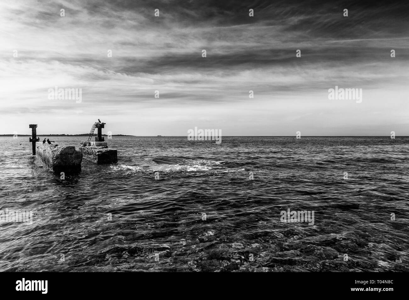 Ancienne jetée abandonnée contre le noir ciel nuageux Banque D'Images