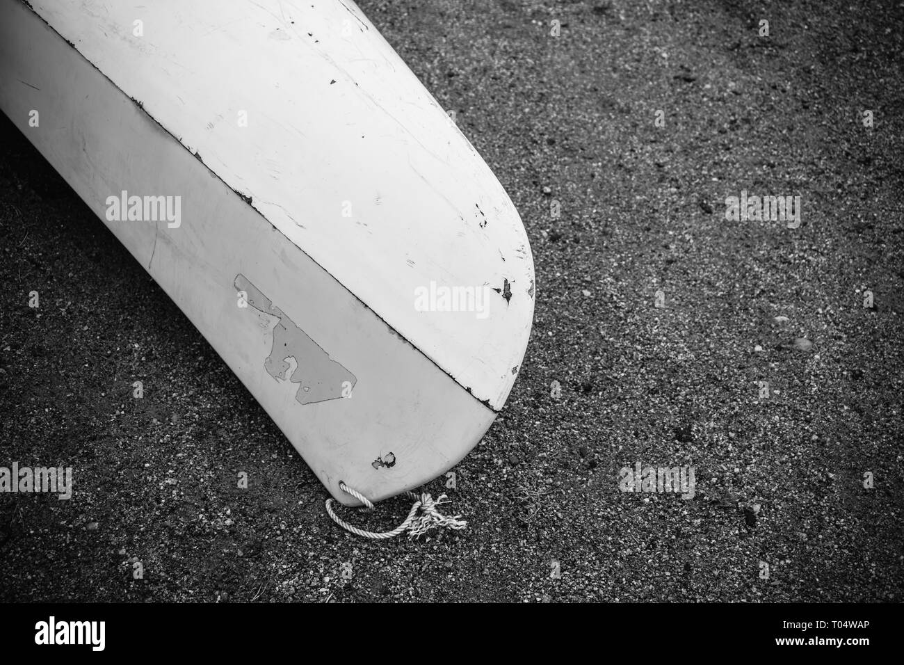 Kayak de plastique en fibre de verre blanc avec de marques avec cordon blanc sur la plage de sable noir avec des pierres sur mer avec aucun peuple, l'arrière-plan Banque D'Images