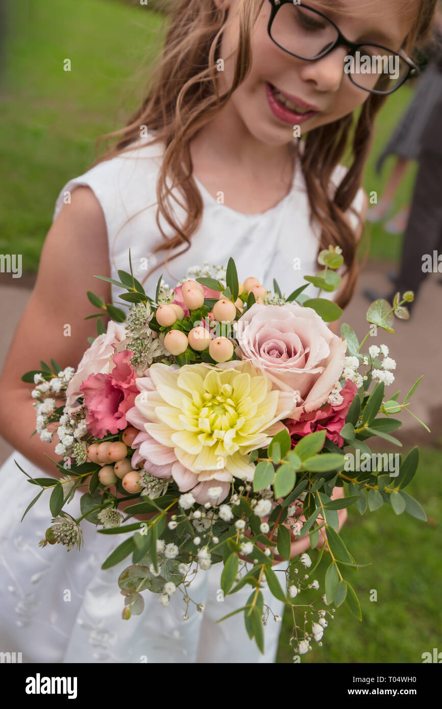 Girl holding de demoiselle petit Septembre saison rustique la main mariage bouquet : roses rose pastel, dahlia, gypsophile, astrantia, baies, feuillage Banque D'Images