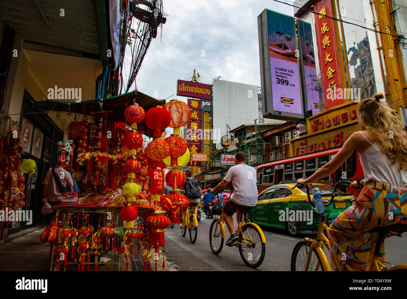 Les touristes se promener avec des vélos jaunes à travers les rues chaotiques de Chinatown à Bangkok, Thaïlande Banque D'Images