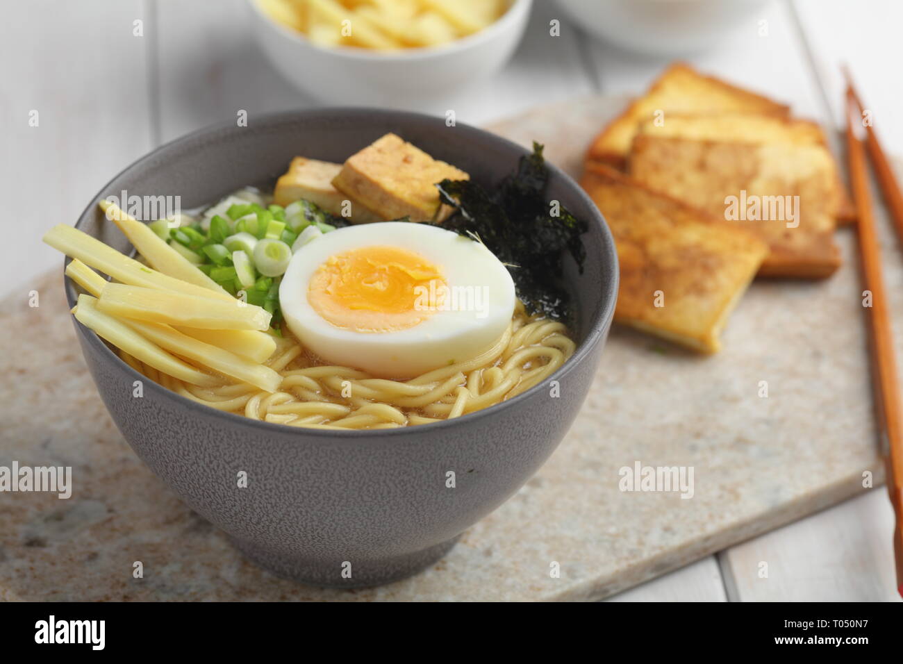 Soupe aux nouilles avec oeuf oeuf mollet, pousses de bambou, du tofu frit, oignon vert, et nori Banque D'Images