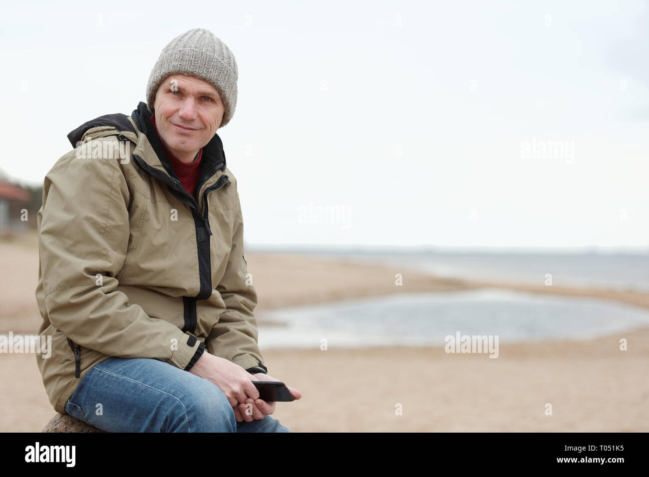 Homme assis avec tablette sur la plage d'hiver Banque D'Images