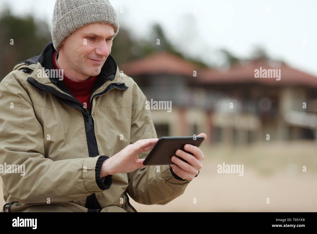 Homme assis avec tablette sur la plage d'hiver Banque D'Images