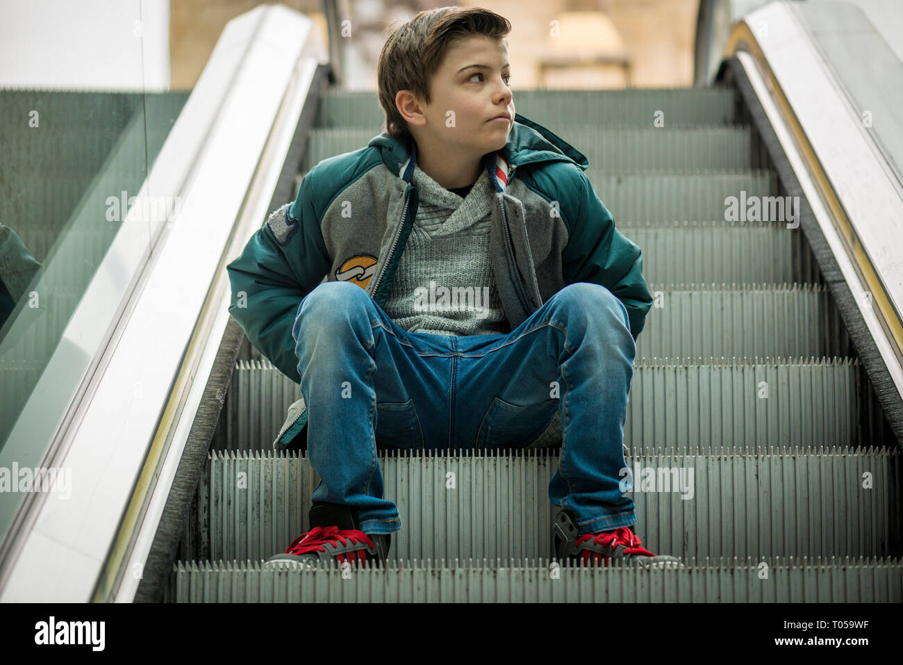 Cool boy sitting on escalator Banque D'Images