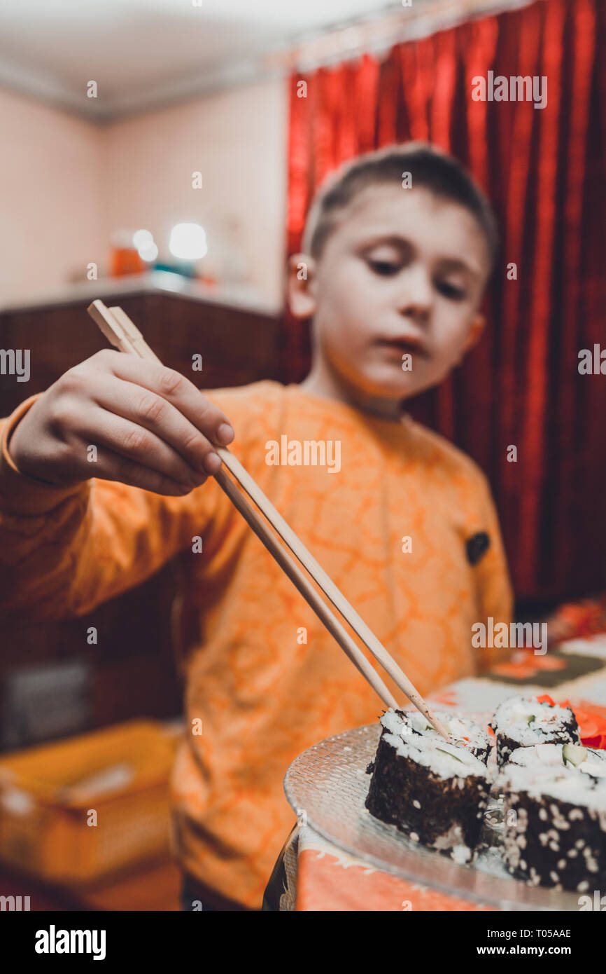 Le jeune garçon prend le rouleau de sushi de la plaque à manger 2019 Banque D'Images