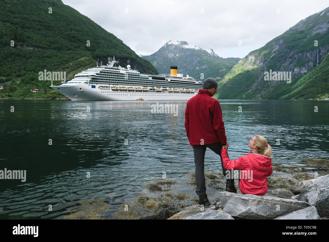 Un paquebot de croisière. Geirangerfjord, près de la ville de Geiranger, Norvège. Jeune couple de voyageurs sur la rive du fjord Banque D'Images